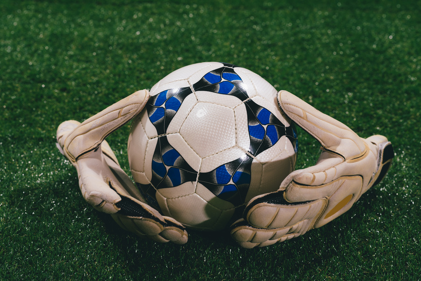 Soccer ball and goalkeeper gloves on the field